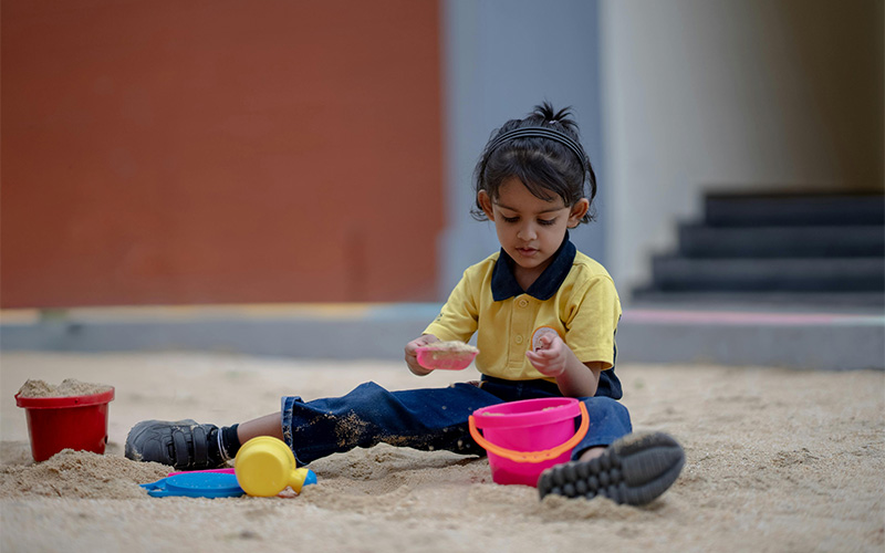 A young child playing in a sandbox with sand toys